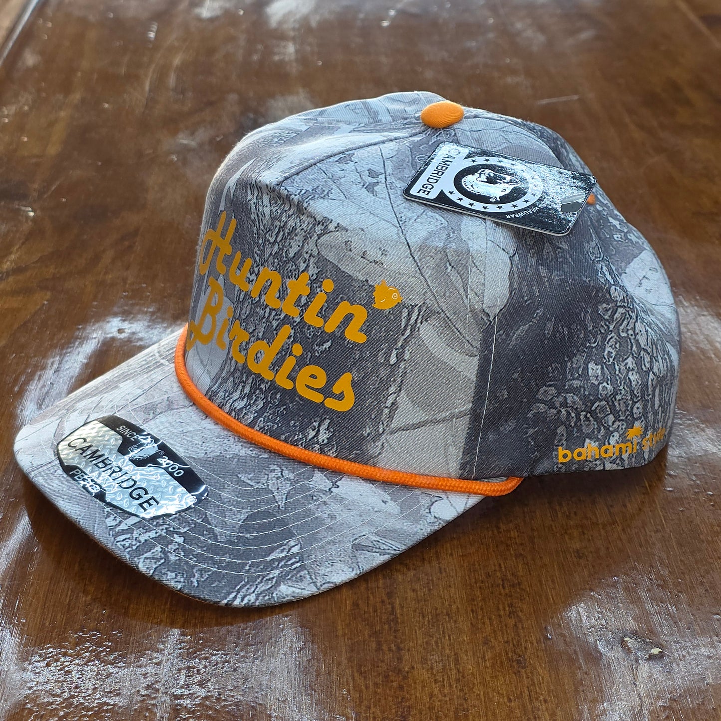 Gray cap with orange brim and branding on a wooden surface
