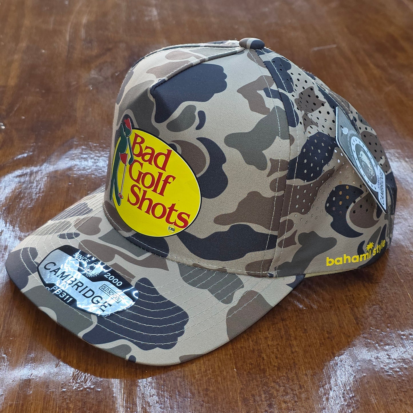 Camouflage-patterned cap with a visible brand logo on a wooden surface