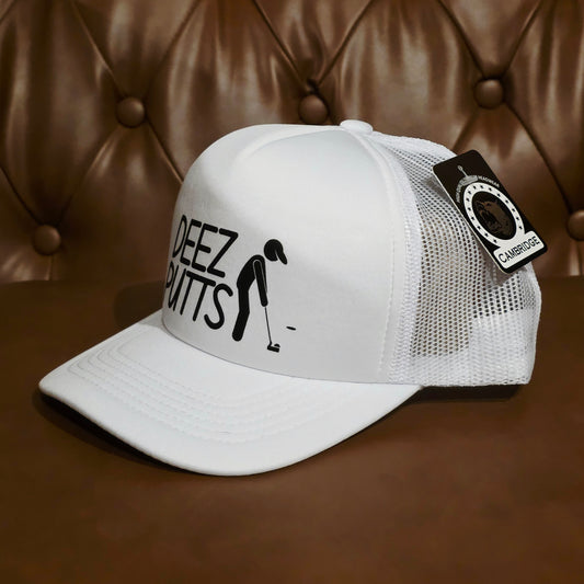 A white trucker-style baseball cap with black printed text reading 'DEEZ PUTTS' and a golfer silhouette on the front, shown on a brown leather tufted surface with a matching brown leather background. A black hangtag is attached to the side.