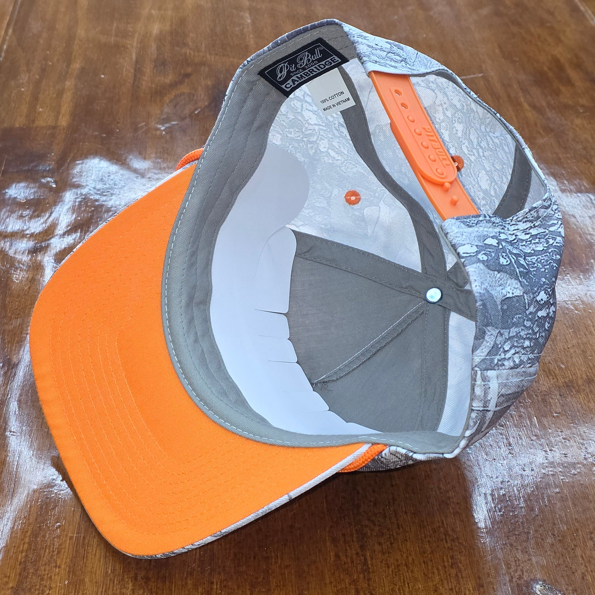 Gray and orange cap on a wooden surface
