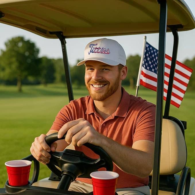 Man driving a golf cart on a golf course with an American flag.
